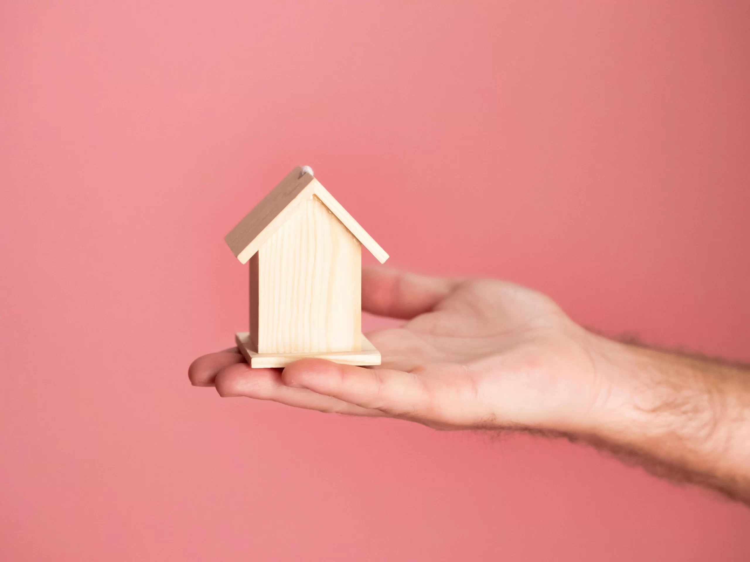 A man holds a small wooden house, symbolizing a Conventional Mortgage Loan West Palm Beach FL.